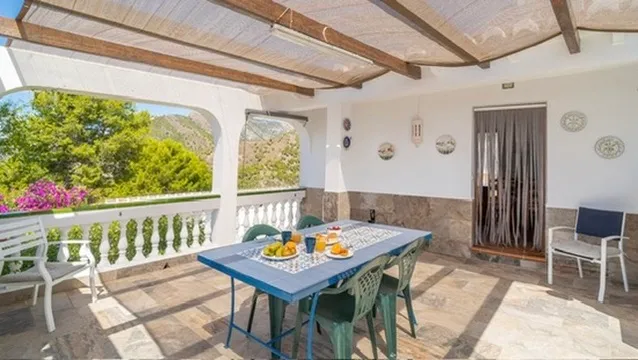 Covered terrace with dining table and garden