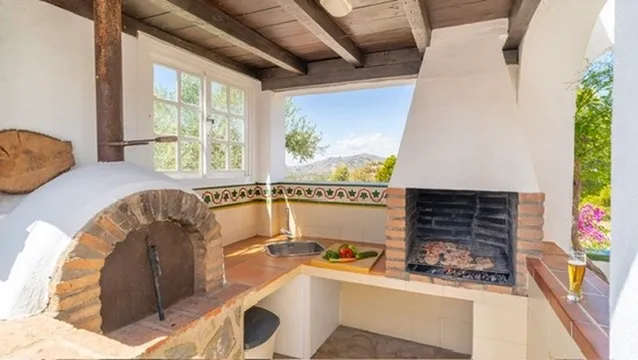 Covered outdoor kitchen with wood-fired oven and barbecue