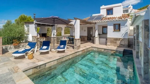 Pool, sun loungers and the house behind