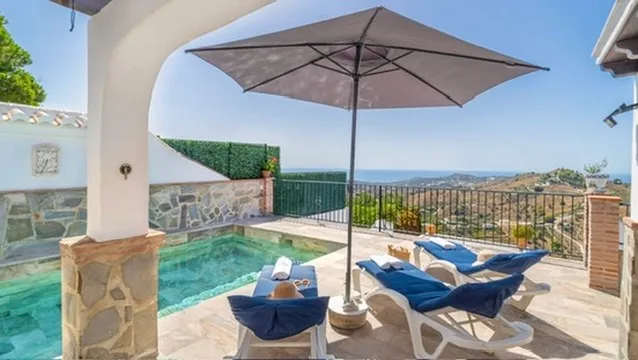 Sun loungers under a parasol facing the sea