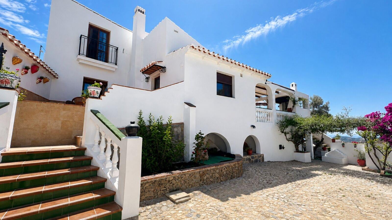 Whitewashed facade of El Olivo, a country house in Frigiliana, Málaga, with tiled staircase and bougainvillea